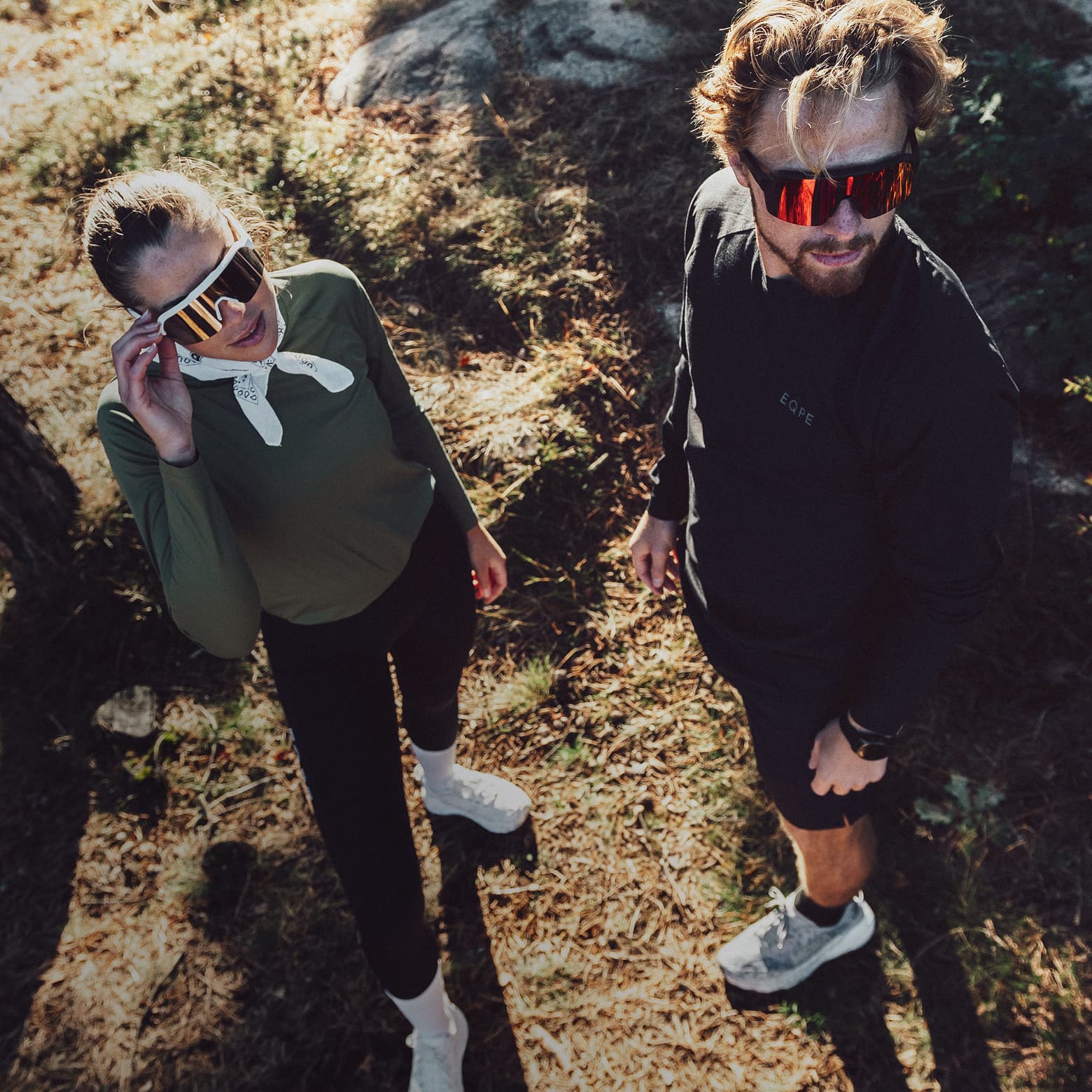 Two people wearing sporty sunglasses and running gear.