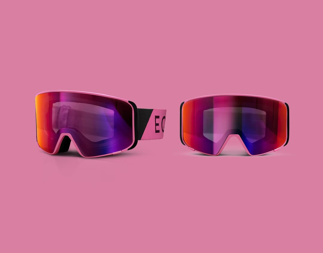 Two pairs of pink ski goggles with reflective lenses on a pink background.