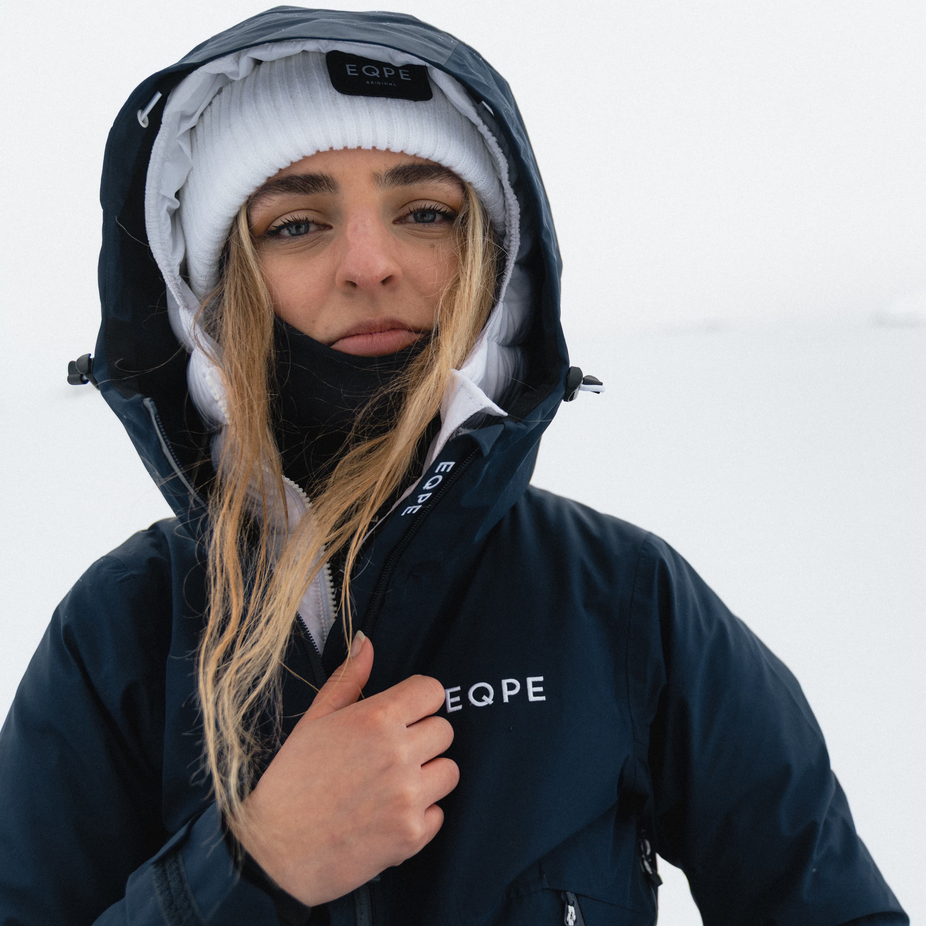 Person in navy hooded winter jacket and white beanie.