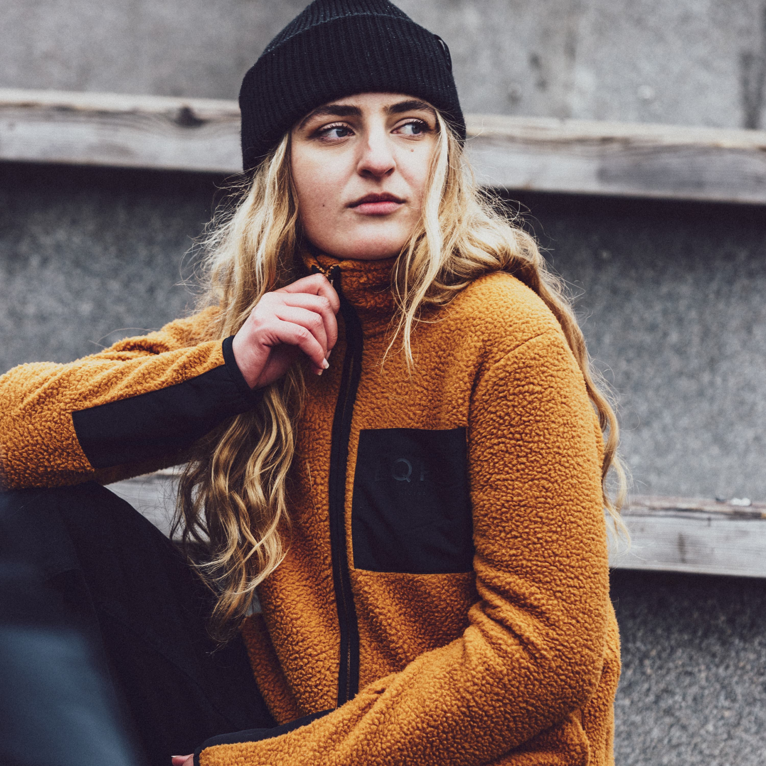 Woman in a fleece jacket and black beanie sitting on steps