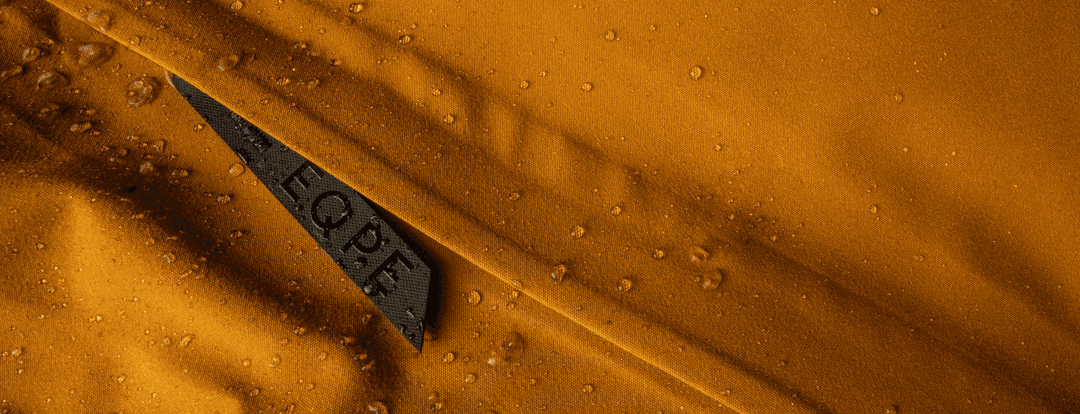 Close up picture of water drops on a water repellent yellow fabric with a zipper, taped seams