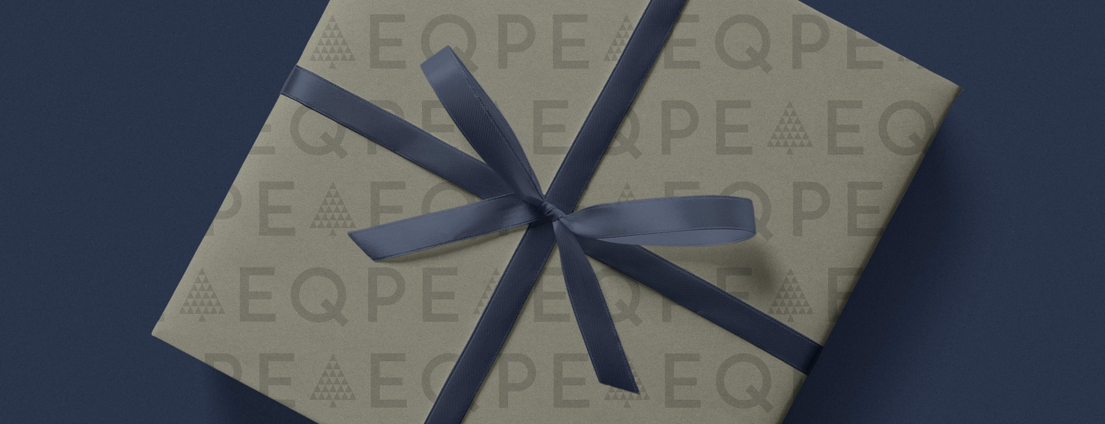 A gift wrapped in patterned paper with "EQPE" and a dark blue ribbon, set against a dark blue background.